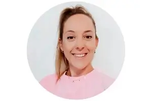 Circular headshot of a smiling woman with her hair pulled back, wearing a pink top.