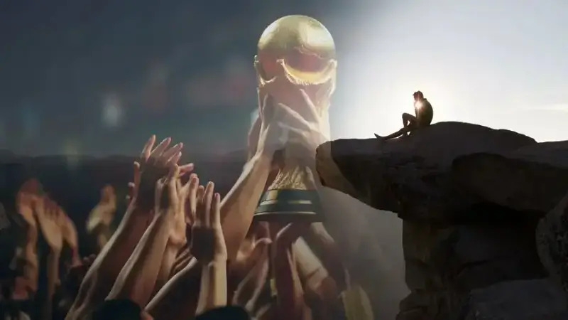 A split-composition image showing a blurred crowd lifting the FIFA World Cup trophy on the left, and a lone silhouette sitting on a rocky cliff edge at sunset on the right.