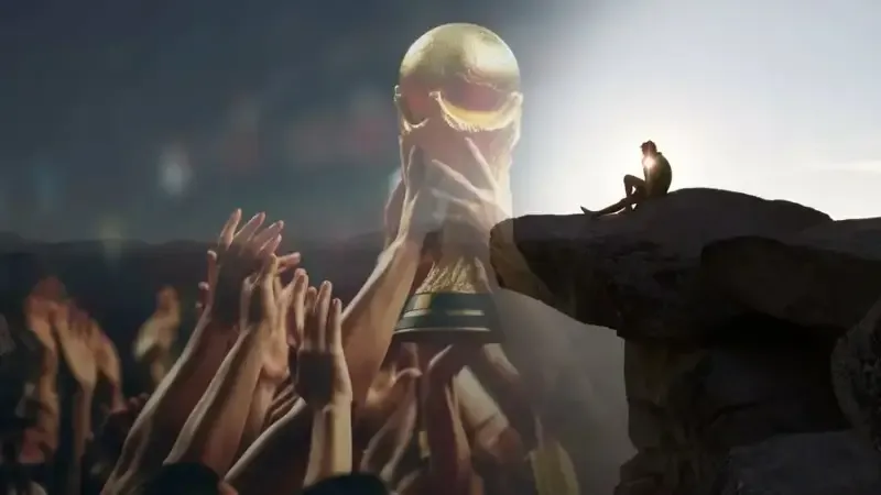 A split digital artwork showing many hands reaching for the FIFA World Cup trophy on the left, and a lone silhouette of a person sitting on a rocky cliff edge at sunset on the right.